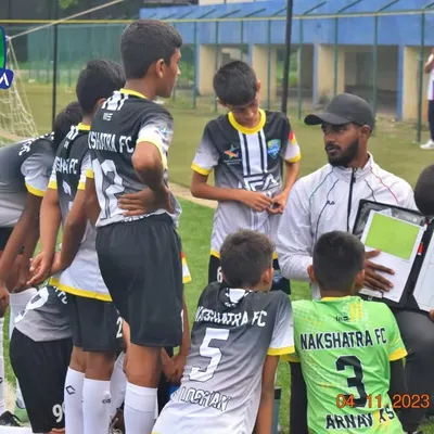 A coach explaining tactics to the U-13 team using a strategy board during a break in the Karnataka Youth Premier League. Game intelligence is as important as physical skill.