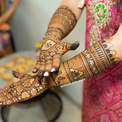 A close-up showing the bride's initial 'V' beautifully integrated into the intricate design on the back of her hand. This is a wonderful way to personalize your mehendi.