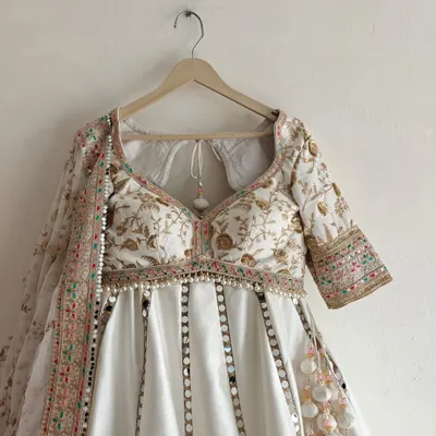 A front view of my white mirror work lehenga, perfect for a day wedding or sangeet. The blouse has a classic sweetheart neckline, and the skirt is adorned with vertical lines of mirror work that beautifully catch the light.