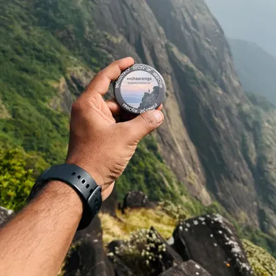 The Kumara Parvatha trek badge held against the dramatic sheer cliffs of the mountain. This trek is not for the faint of heart, but the views are epic.