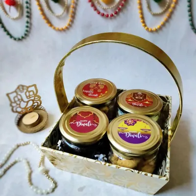 This is my classic four-jar Diwali hamper, beautifully arranged in a golden basket. It includes two cake jars, pistachio nankhatai, and peri peri makhana, all with festive 'Happy Diwali' labels.