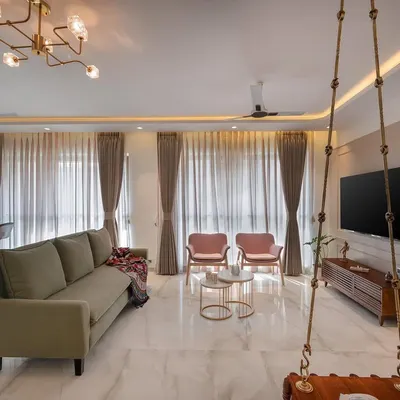 We love the cheerful vibe of this pastel-themed living room. The combination of the olive green sofa, pink armchairs, and a traditional wooden swing creates a space that is both chic and deeply personal.