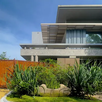 The 'STILL HOME' in Tiruppur, where shades of grey create a sense of peace and stillness. The design uses a rich palette of textures, including exposed concrete, GFRC panels, and corten steel, all unified by a monochrome theme.