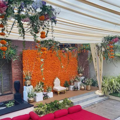 An outdoor Haldi ceremony setup featuring my signature dense marigold wall. The stage is complemented by a floral chandelier and comfortable floor seating, creating a festive and inviting space for guests.