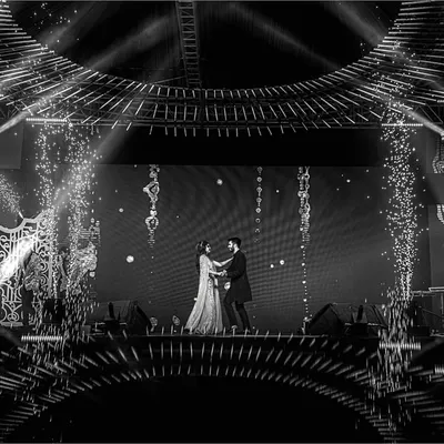 A grand stage, dramatic lighting, and a couple lost in their dance. This shot captures the epic scale and cinematic feel of a Sangeet performance, complete with pyrotechnics.
