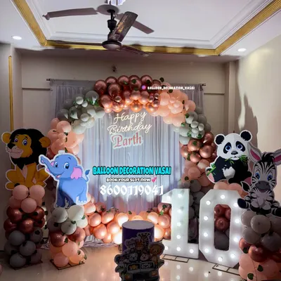 A jungle animal theme for Parth's 10th birthday. This home setup features a balloon arch in rose gold and pastel colors, with cutouts of a lion, elephant, panda, and zebra.