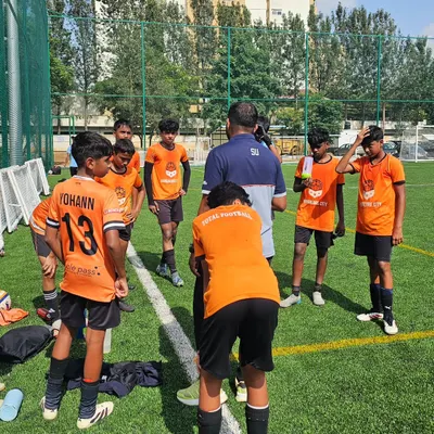 Tactics, teamwork, and our Total Football philosophy in action. A coach briefs the team during a water break, ensuring every player understands their role on the pitch.