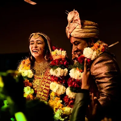 The varmala ceremony is full of laughter and joy. I captured this candid moment of the couple sharing a laugh, surrounded by friends and family. This is the kind of spontaneous, happy memory I aim to preserve from your wedding day.