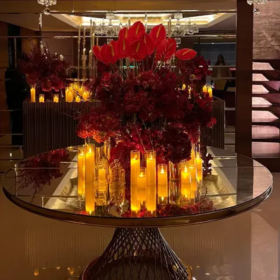 For a luxurious home birthday, we created a dramatic atmosphere using masses of crimson flowers and glowing candles on mirrored and metallic surfaces to reflect the light beautifully.