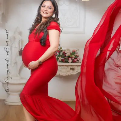 A vibrant red gown brings such life and energy to a maternity portrait. The flowing fabric adds a touch of drama, perfectly highlighting the baby bump in this studio shot.