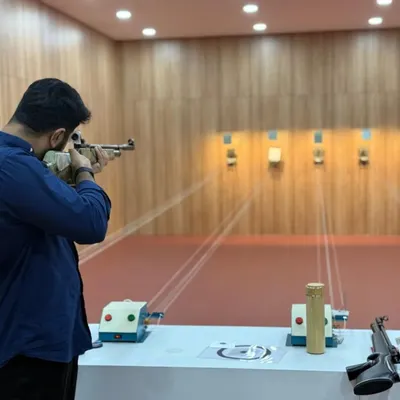 A shooter takes a focused stance, aiming down the sights of the air rifle. This moment of intense concentration is what the sport is all about.