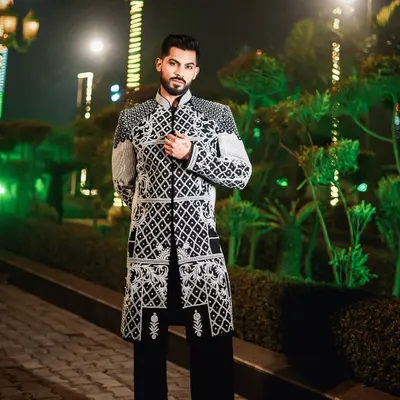 A masterpiece of modern royalty. This black Indo-Western jacket is defined by its intricate ivory hand-embroidery and lustrous embellishments, a testament to our commitment to unparalleled craftsmanship for the discerning groom.