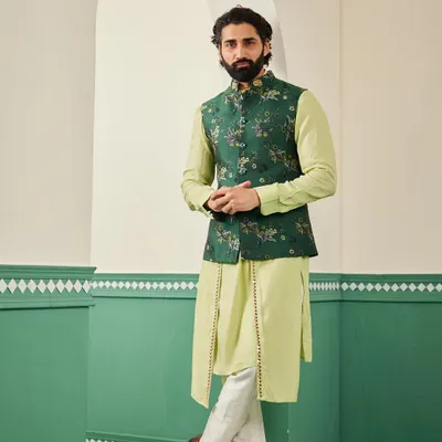 The emerald green bundi set, a perfect choice for mehendi or sangeet functions. The rich green of the embroidered jacket contrasts beautifully with the light green draped kurta.