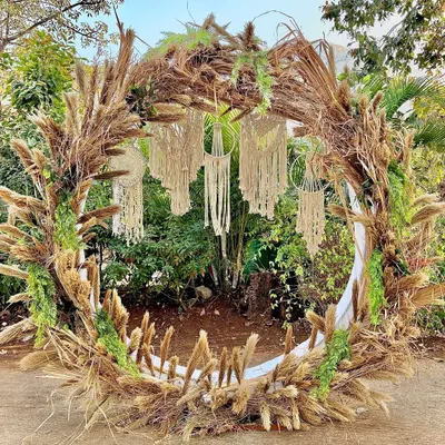 We created this stunning bohemian-themed photobooth with a circular frame made of dried pampas grass and wheat stalks. The hanging macrame dreamcatchers in the center complete the free-spirited, rustic vibe.