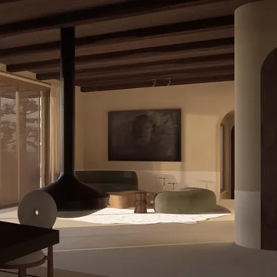 A view of the living space at Can Benet in Ibiza, featuring a suspended fireplace that acts as a sculptural centerpiece. The design connects the interior with the surrounding landscape through large glass doors.