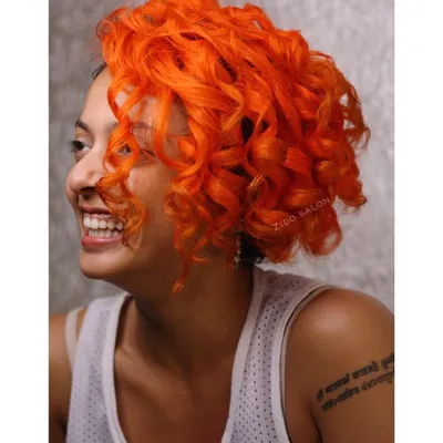 This vibrant orange on beautiful curls is what we call 'Summer is Here'. We used a high-impact neon orange to create a look that's as bright and energetic as our client.