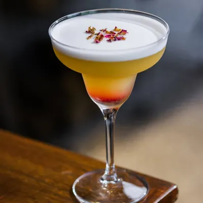 This is my Almafi mocktail, a layered drink with a frothy top and a sprinkle of dried rose petals. It's a light and refreshing choice, perfect for sipping slowly on a warm day.