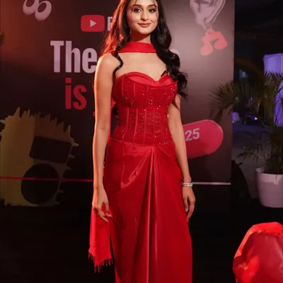 A full-length shot of Payal Gaming at the YouTube Fanfest, showcasing how the complete makeup and hair look comes together with her stunning red gown for a cohesive and show-stopping red carpet presence.