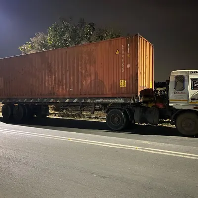 The journey begins. A 40-foot shipping container arrives on a truck at night, ready to be repurposed into a key component of a new architectural project.