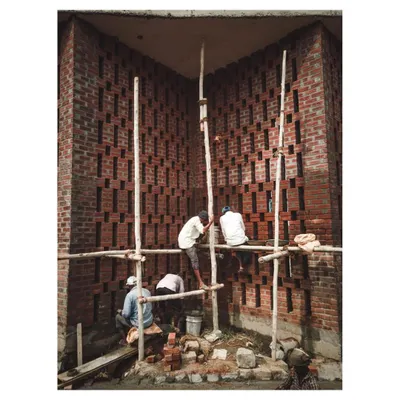 Masons at work on the intricate brick jali wall of the Dr. Vishnuvardhan Memorial. This image captures the human skill and craftsmanship involved in realizing the design.