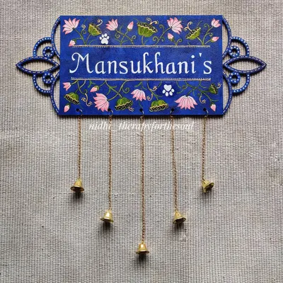 This nameplate features delicate Pichwai-inspired lotus motifs on a deep blue background. The laser-cut MDF base with its ornate edges was also designed by me, and the hanging bells add a final charming touch.