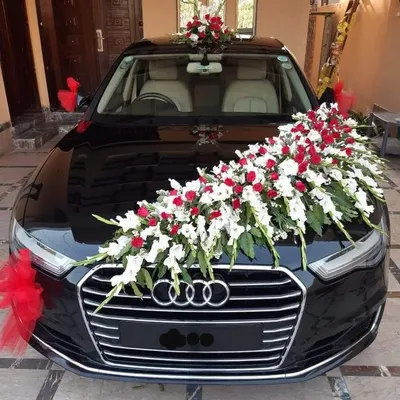 A classic and elegant decoration for a black Audi. The arrangement features a cascade of white gladiolus and red roses across the bonnet, with matching red ribbons on the side mirrors for a complete look.