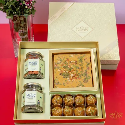 This premium gift hamper is a perfect example of my festive collection. It includes a box of my signature mithai, Panjiri Laddoos, and two jars of savory nuts, all presented in an elegant box ready for gifting.