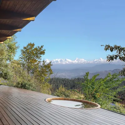 A Himalayan mountain home we designed, featuring a deck with a hot tub that looks out onto snow-capped peaks. The architecture is designed to be a viewing platform for the majestic landscape.