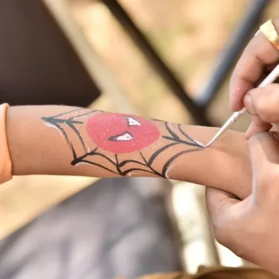 A young superhero in the making. Here, an artist is putting the finishing touches on a Spiderman web design, a very popular request at my parties. We can paint all sorts of fun designs.
