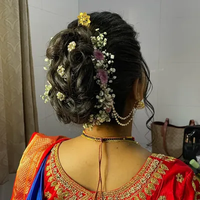 A detailed view of a beautiful textured bun for a Marathi bride. The hairstyle is adorned with delicate baby's breath and other small flowers for a romantic touch.