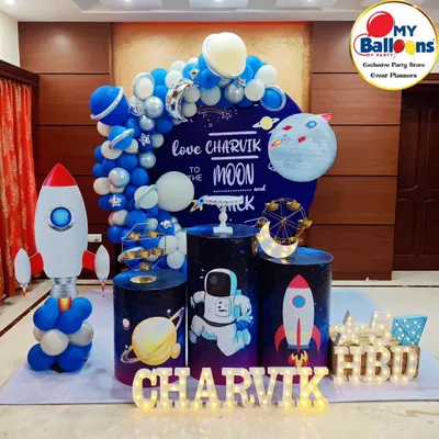 A stellar space-themed fifth birthday party. This setup features a "Love you to the moon and back" backdrop, a rocket ship balloon sculpture, and astronaut-themed plinths.