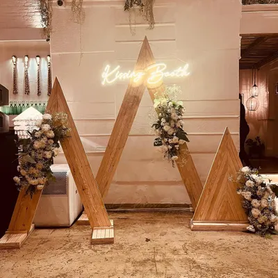 This custom-designed wooden arch with a "Kissing Booth" neon sign was the highlight of a 25th-anniversary celebration. It served as a perfect photo opportunity, blending rustic charm with modern elegance.