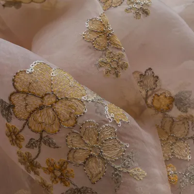 The rich gold threadwork on this blush pink organza creates a truly regal effect. The floral motifs are detailed with sequins, adding a touch of sparkle perfect for a wedding lehenga or a grand anarkali.
