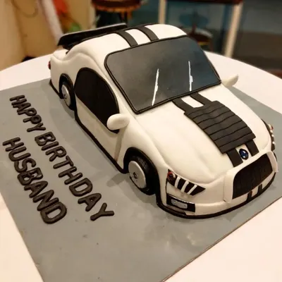 A fully sculpted 3D sports car cake, custom-made for a husband's birthday. Every curve and detail of the car is carved and decorated by hand to create a realistic and impressive centerpiece.