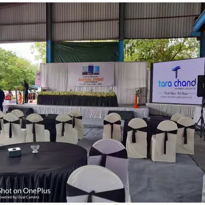 The stage and seating view for the Tara Chand InfraLogistics annual event. You can see the main stage with its floral decor and the large LED screen displaying the company's branding.