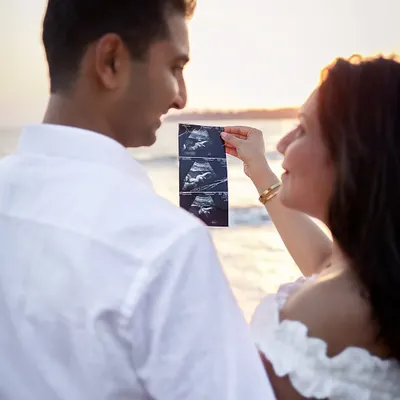 A close-up of the first family photo. Using your ultrasound scan during a beach sunset shoot is a deeply personal and beautiful way to announce your pregnancy.