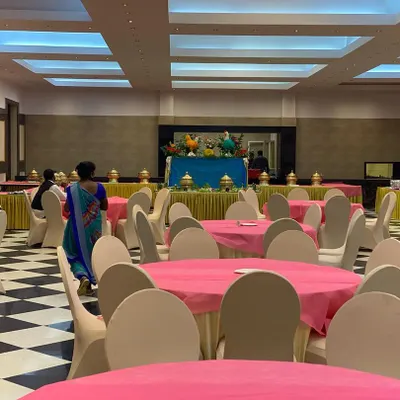A spacious indoor wedding hall setup at CMA Palace, ready for guests. We arranged the seating with vibrant pink tablecloths to match the client's theme, ensuring the venue looked festive and welcoming.