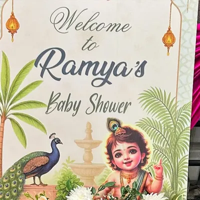A traditional and artistic welcome sign for a baby shower, featuring a beautiful illustration of baby Krishna and a peacock.