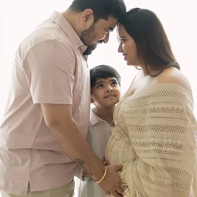 A beautiful moment of connection between expecting parents, with their son looking up at them. This image tells a story of a family eagerly awaiting their new arrival.