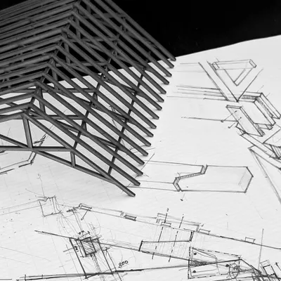 A physical model of a roof truss sits atop its corresponding architectural drawings. This juxtaposition of the tangible and the conceptual is at the heart of my design process, where ideas are constantly tested between different modes of representation.