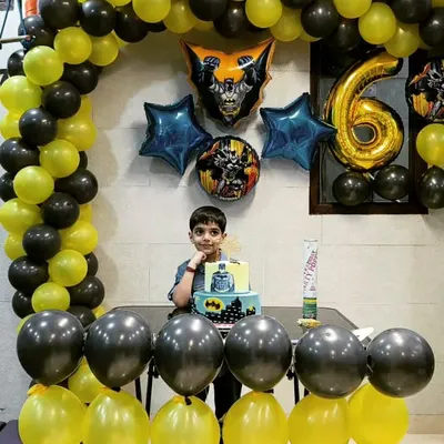 The birthday boy posing with his Batman-themed cake in front of a matching black and yellow balloon arch. We go all-in on creating the perfect superhero headquarters for your child's special day.