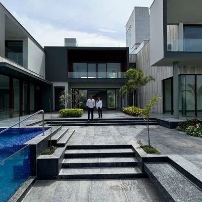 The central courtyard of the Rosewood Farmhouse, viewed from the pool area. The design creates a seamless flow between different zones, with wide steps and open passages that encourage movement and connection. The architecture frames views of the landscape, making the entire property feel like a cohesive, luxurious retreat.