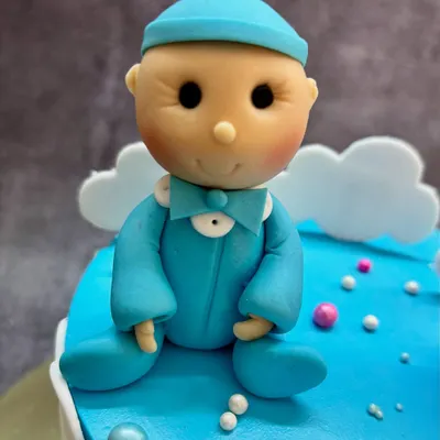 A close-up of the adorable baby boy topper for a gender reveal cake. I handcraft these little figures from fondant to make your surprise extra sweet.