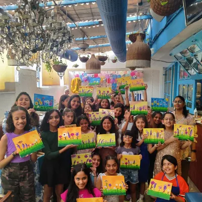 A large, happy group of children at Nishka's 10th birthday party, all holding the beautiful floral canvases they painted. A birthday art party is a fantastic way for kids to celebrate and create something they can be proud of.