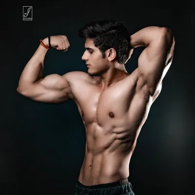 A classic side bicep pose, expertly lit to emphasize the peak of the bicep and the striations in the shoulder and chest. This is a fundamental shot for any competitive bodybuilder's portfolio.