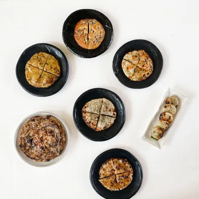 Our kulchas have a following of their own. This overhead shot shows a variety of our stuffed breads, from classic potato to inventive blue cheese, each quartered and ready for sharing.