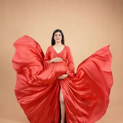 A dramatic and powerful solo portrait. The flowing red gown creates a stunning visual effect, celebrating the strength and beauty of the mother-to-be.