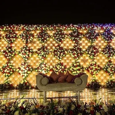 This is one of my most requested wedding stage designs, featuring a full wall of red and white flowers with beautiful embedded lights. The luxurious sofa provides the perfect seating for the couple on their special day.