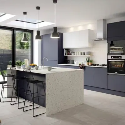 This spacious kitchen features a large island with a waterfall countertop that doubles as a breakfast bar. The matte navy cabinets and integrated appliances create a sophisticated, seamless look perfect for modern living.