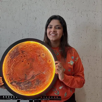 The finished Mars lamp, glowing with its integrated LED backlight. The light catches the textured craters and canyons, creating a warm and dramatic effect. This piece is a conversation starter.